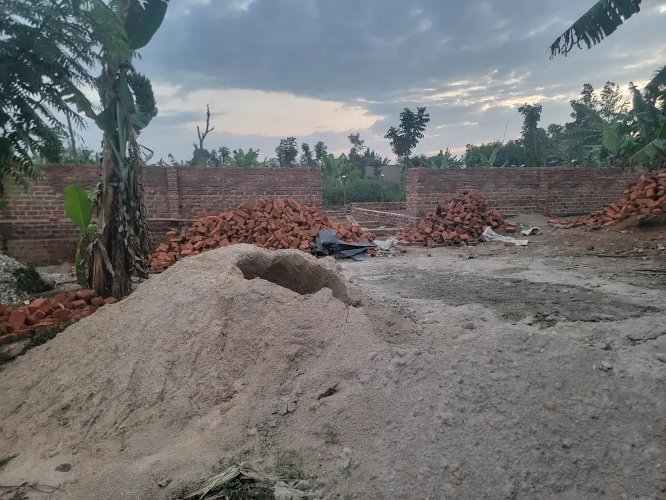 Brick walls of the boys’ dormitory rising on site, with piles of bricks and sand in front.